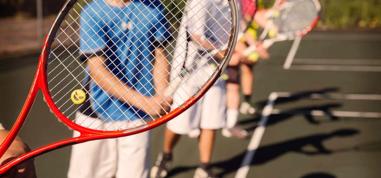 Group of juniors holding up tennis racquet